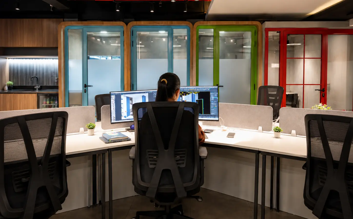 Person working at a coworking desk at Spunic Kondotty, with private cabins and a pantry behind